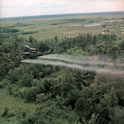 A helicopter sprays foliage with Agent Orange in an undated photo taken during the Vietnam War. (Photo via Shutterstock)